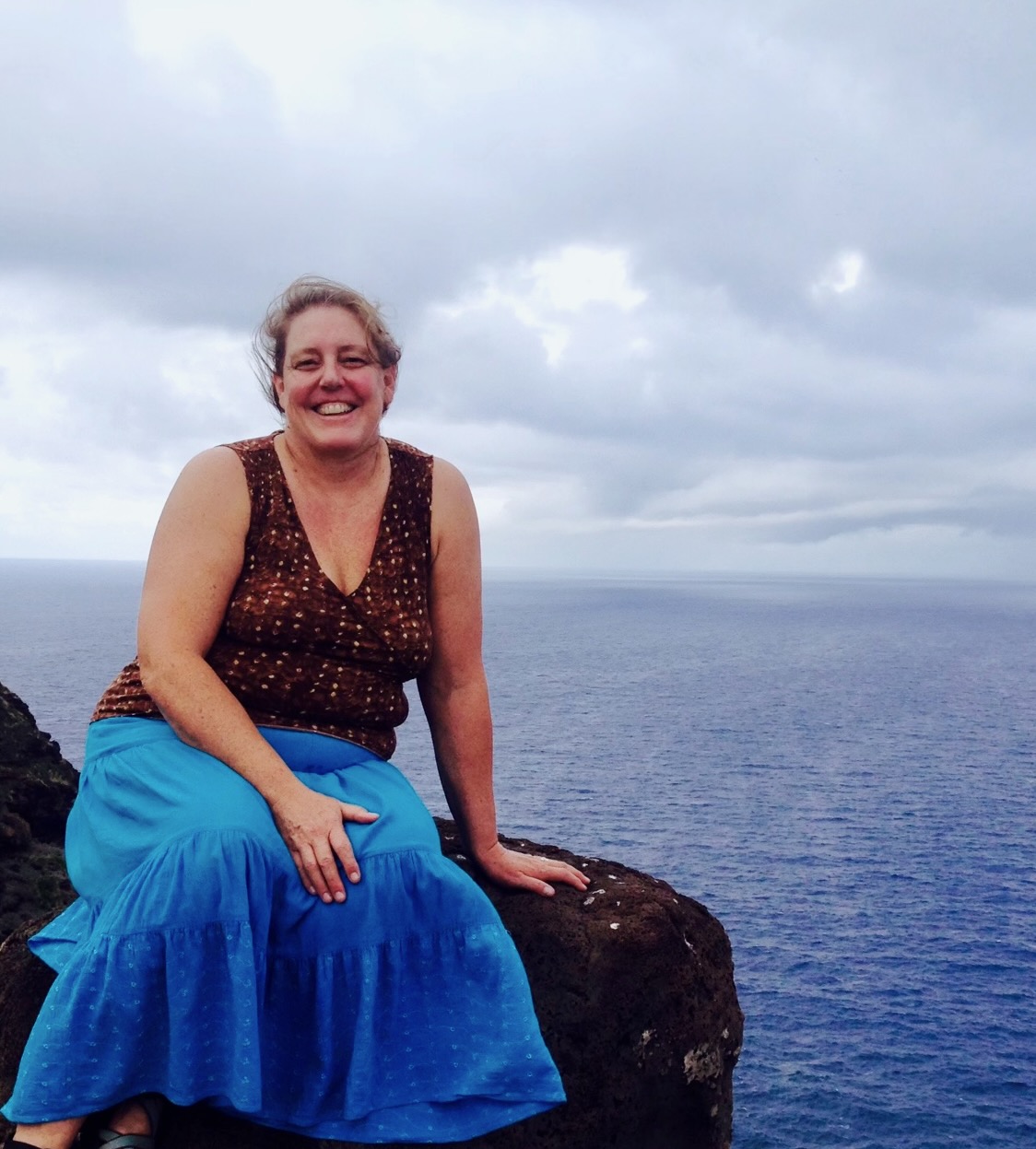 Susanne One Love sitting on a rock at the beach